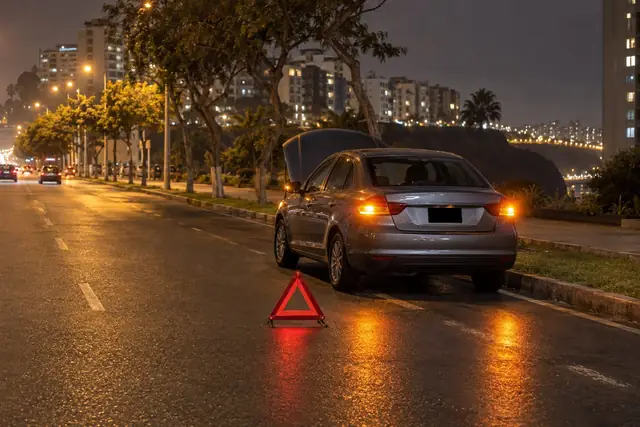 Auto detenido en la vía de noche, con el capó abierto y un triángulo de seguridad