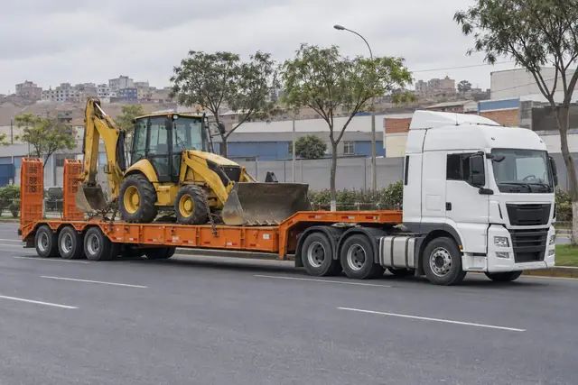 Grúa cama baja con una retroexcavadora